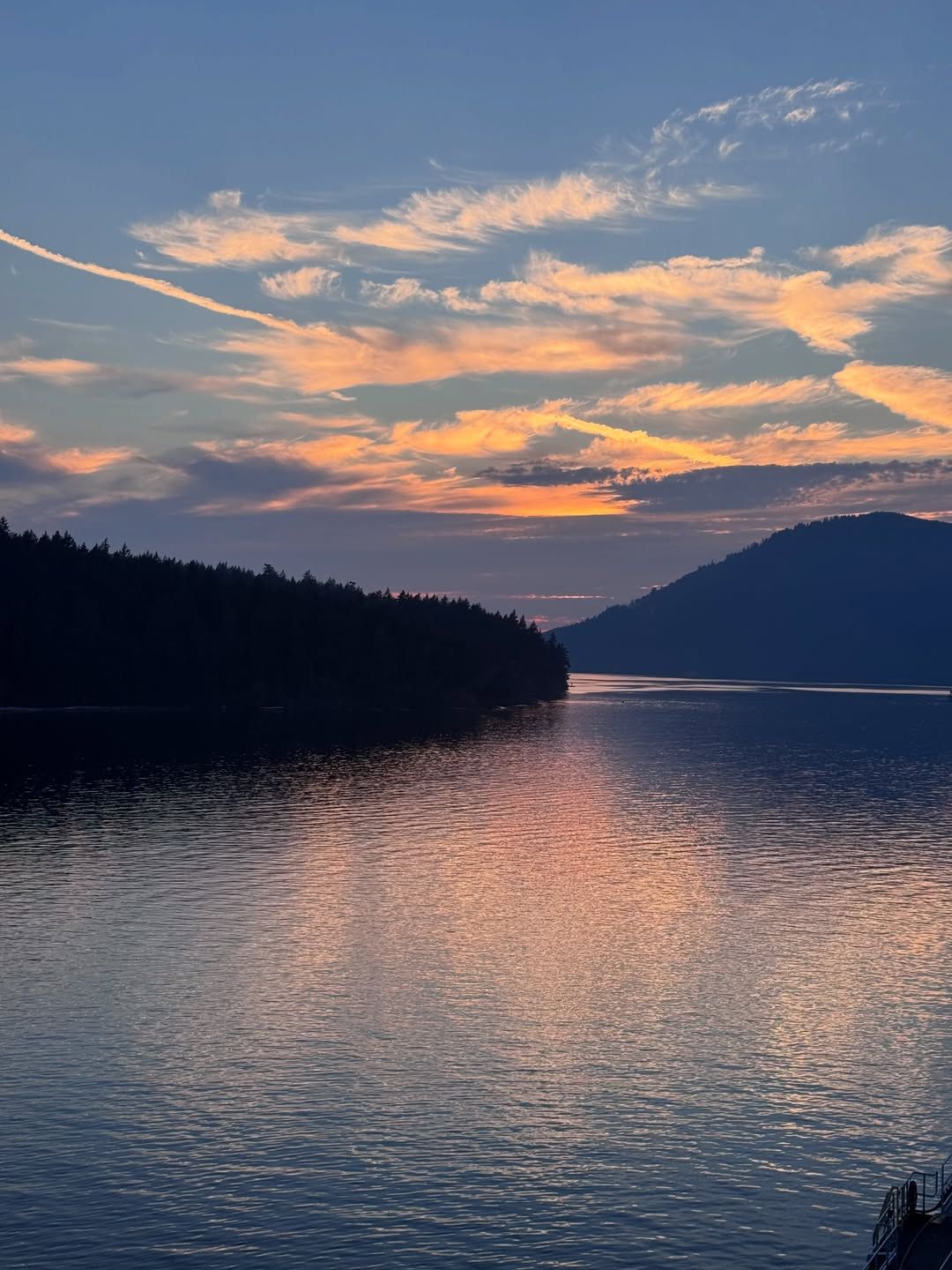 Lake and forested mountains glow in golden sunset light.