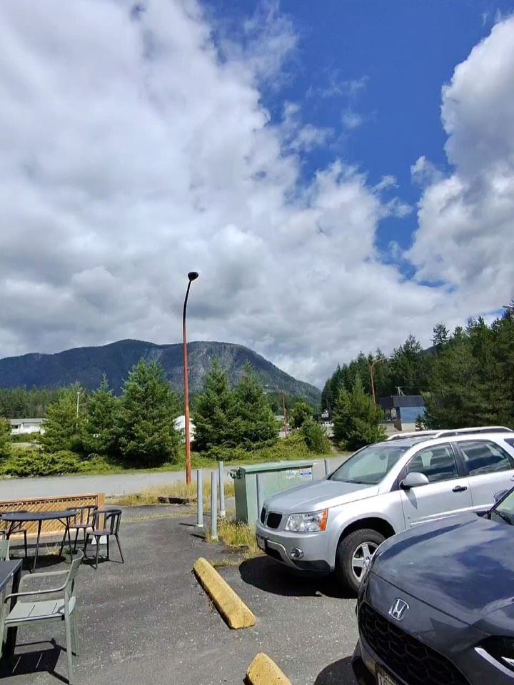 Mountains with forested slopes frame a mountain valley parking area.