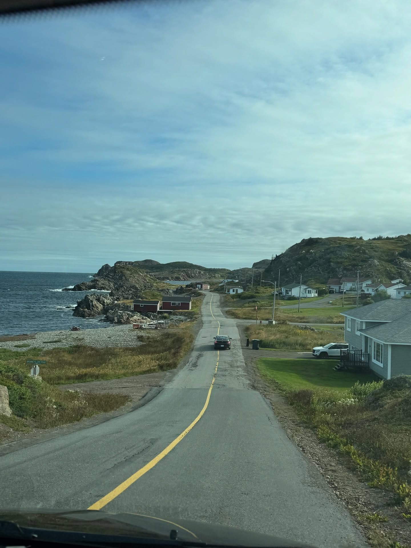 Coastal village with boats, houses, and rocky shoreline under blue sky.
