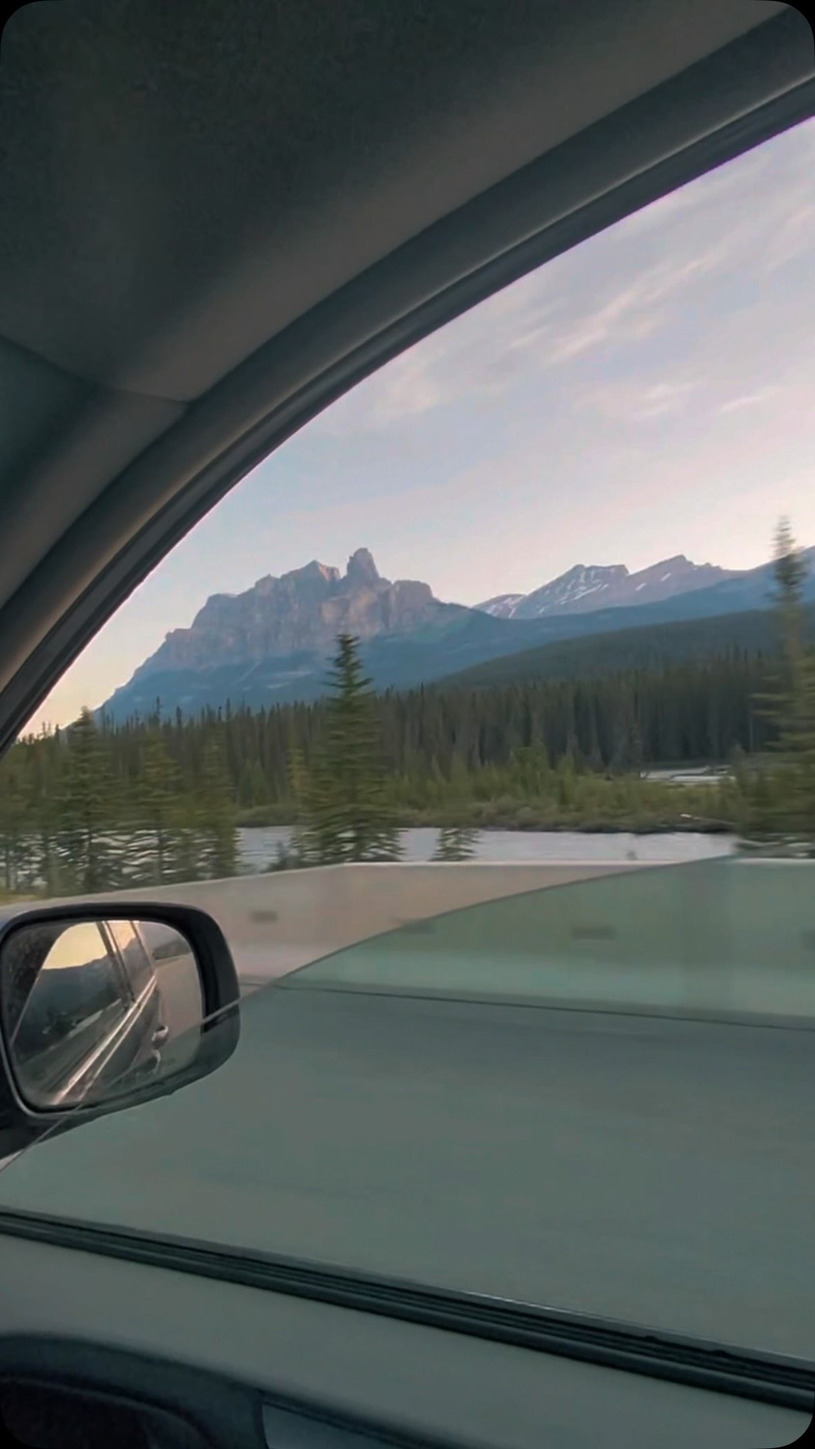 View from van window of mountains, forest, and alpine lake.