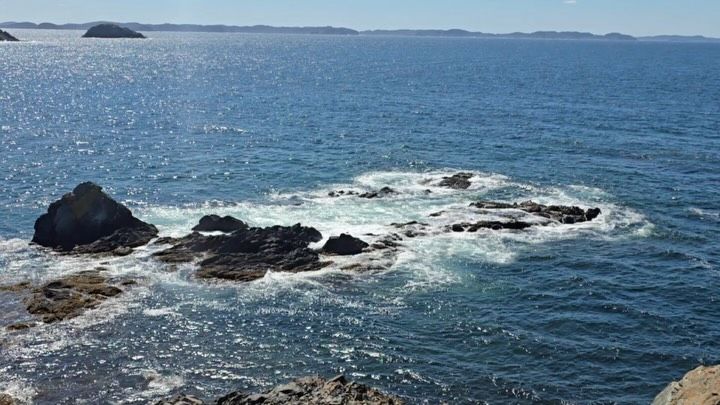 Dark rocks and waves crashing on a rocky ocean coastline.