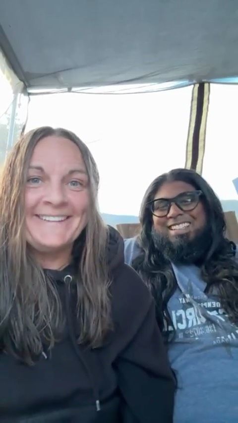 Woman with brown hair and woman with black hair smiling inside van.
