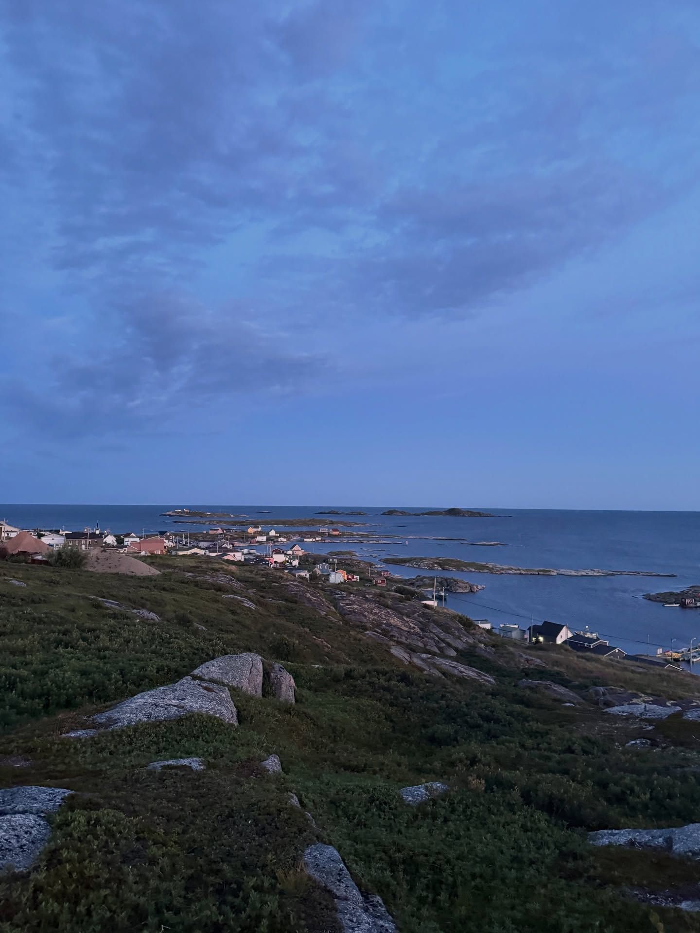 Red-roofed village nestled along a rocky coastline with ocean and sky.