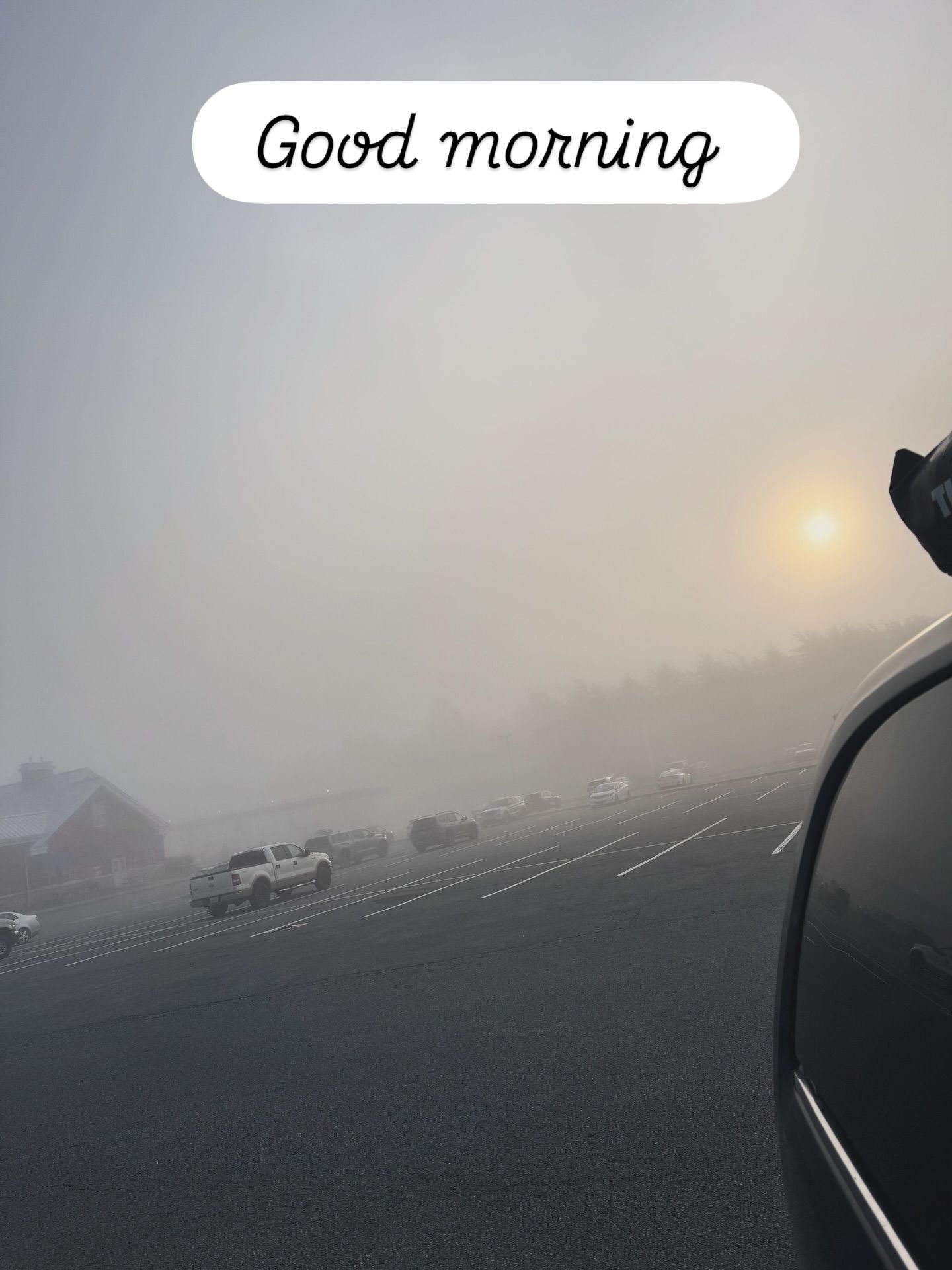 Van drives foggy highway at sunrise with other traffic visible ahead.