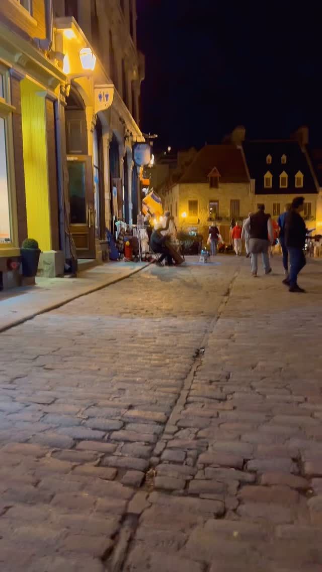 Historic town square illuminated at night with distinctive architecture and people.